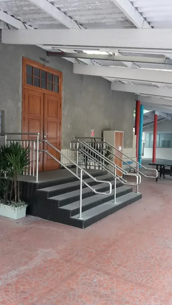 Corrimão duplo em aço inox em acesso com degraus de ambiente institucional
